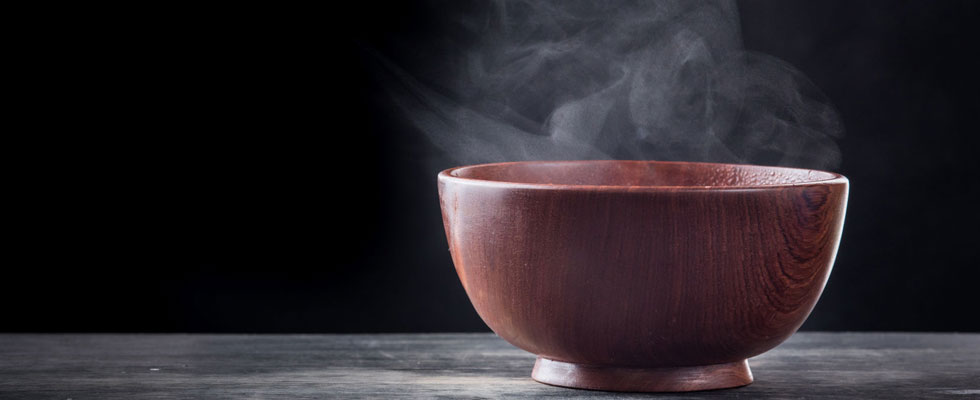 bamboo bowl with steam on black background